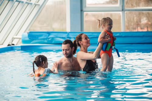 a man and woman holding a child in a swimming pool at HOTEL AGRI in Soběšice