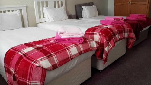 two beds in a hotel room with pink towels on them at Eliza House in Edinburgh