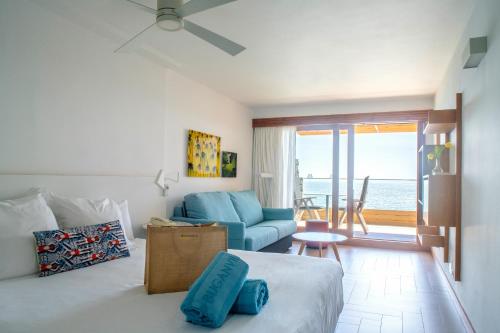 a bedroom with a bed and a living room with the ocean at Apartamentos Buganvilla - Adults Only in San Agustin