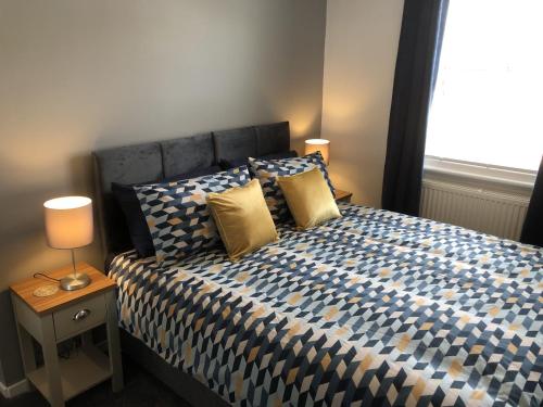 sypialnia z łóżkiem z żółtymi poduszkami i oknem w obiekcie Hattie's Cottage w mieście Lincoln