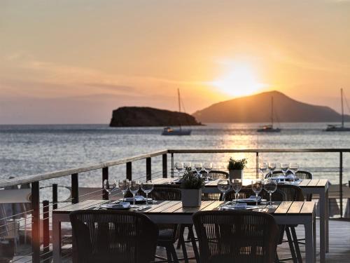 una mesa con copas de vino y el océano al atardecer en Aegeon Beach Hotel, en Sounio