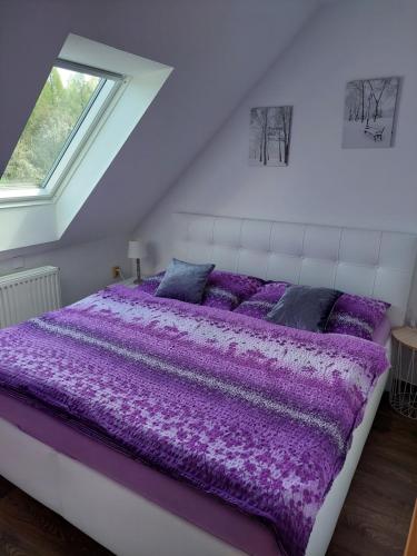 Cama grande morada en habitación blanca con ventana en Ubytování u Solárky, en Trojanovice