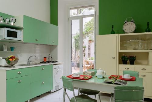 une cuisine avec des placards verts et une table avec des chaises dans l'établissement Petrucci Garden by Enjoy Napoli, à Naples