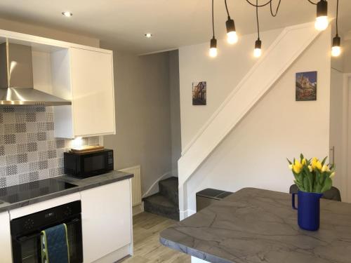 a kitchen with white cabinets and a table with yellow flowers at Hattie's Cottage in Lincoln