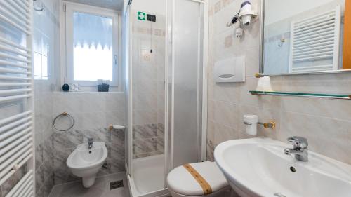 a white bathroom with a sink and a toilet at HOTEL DOLOMITI di De Martin D Oscar in Comèlico Superiore