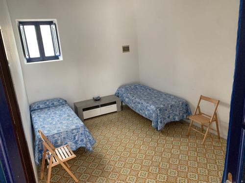 Zimmer mit 2 Betten, einem Tisch und einem Stuhl in der Unterkunft Casa Cristian Stromboli in Stromboli