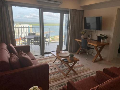 a living room with a couch and a large window at Sky high with harbour views in Darwin
