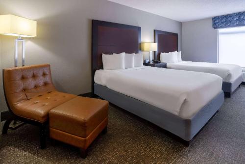 a hotel room with two beds and a chair at Wingate by Wyndham Atlanta Galleria/ Ballpark in Atlanta