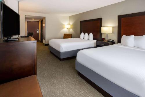 a hotel room with two beds and a flat screen tv at Wingate by Wyndham Atlanta Galleria/ Ballpark in Atlanta