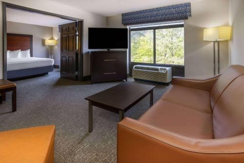 a hotel room with a couch and a bed and a television at Wingate by Wyndham Atlanta Galleria/ Ballpark in Atlanta