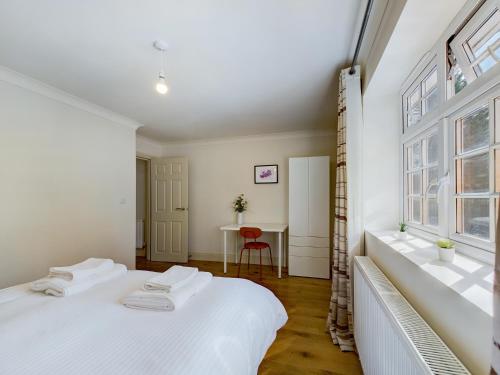 duas camas num quarto com uma mesa e uma janela em Duplex Redhill town centre Apt by Livingo Stays em Redhill