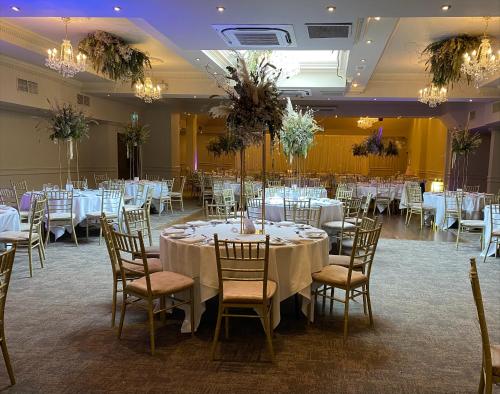 um salão de banquetes com mesas e cadeiras brancas e lustres em Abbey Court em Nenagh