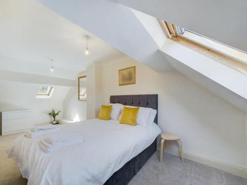 a bedroom with a large white bed with yellow pillows at Duplex Redhill town centre Apt by Livingo Stays in Redhill