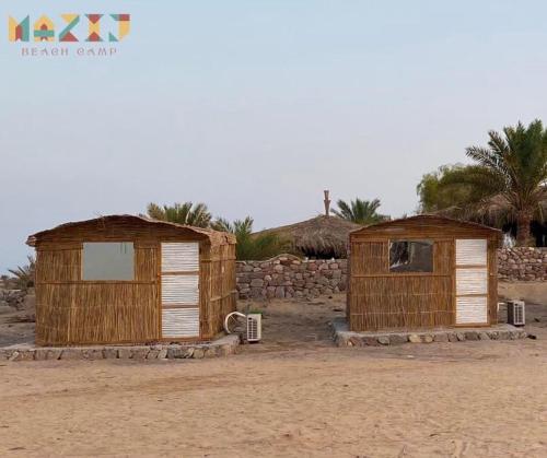 dos cabañas de madera sentadas en la arena en el desierto en Mazih beach camp, en Nuweiba