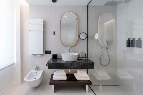 a white bathroom with a sink and a mirror at Radisson Collection Hotel, Santa Sofia Milan in Milan