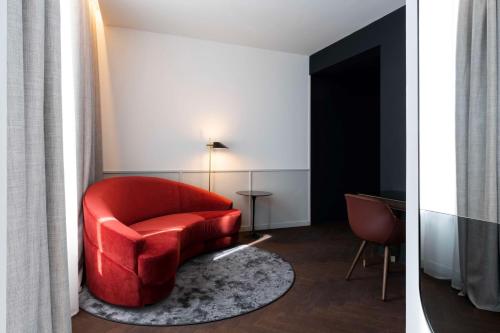 a living room with a red chair and a table at Radisson Collection Hotel, Santa Sofia Milan in Milan
