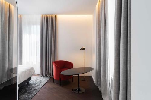 a hotel room with a table and a red chair at Radisson Collection Hotel, Santa Sofia Milan in Milan