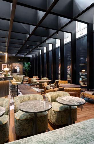 a lobby with tables and chairs and windows at Radisson Collection Hotel, Santa Sofia Milan in Milan