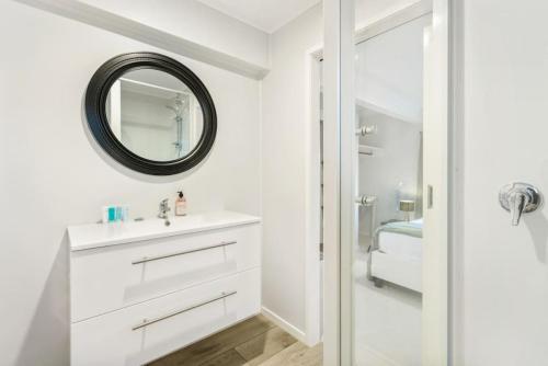 Baño blanco con lavabo y espejo en A delight in the Bays - 1 BR - 1 BATH - Free WiFi, en Auckland