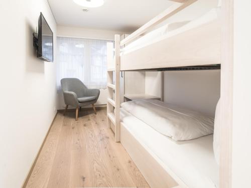 a small bedroom with bunk beds and a chair at Traube Restaurant & Hotel in Appenzell