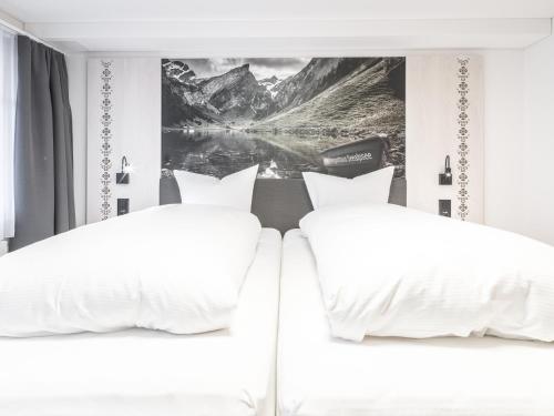two white beds in a bedroom with a picture on the wall at Traube Restaurant & Hotel in Appenzell