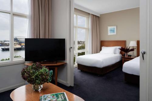 a hotel room with two beds and a flat screen tv at Rydges Newcastle in Newcastle