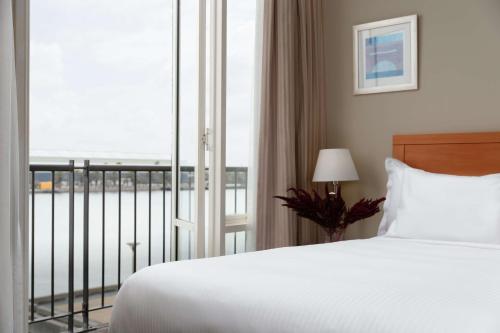 a bedroom with a bed and a window with a balcony at Rydges Newcastle in Newcastle