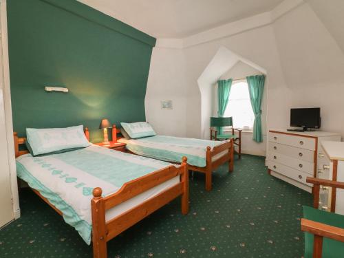 2 camas en una habitación con una pared verde en Beaufort House, en Ilfracombe