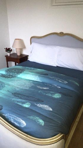 a bed with a blue blanket with footprints on it at Gîte La vie au vert Spacieux et autonome in Malay-le-Grand