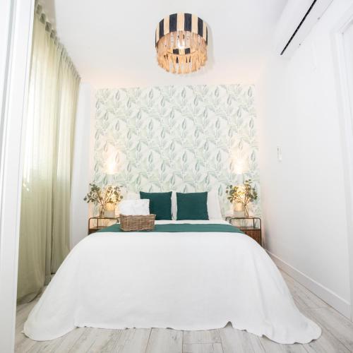 a bedroom with a white bed and a chandelier at Hostal Benalup Atalaya in Benalup Casas Viejas