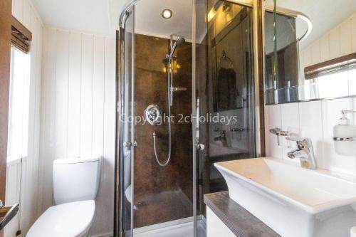 a bathroom with a shower and a toilet and a sink at Luxury Lodge With Stunning Sea Views At Hopton Haven Park Ref 80055s in Great Yarmouth