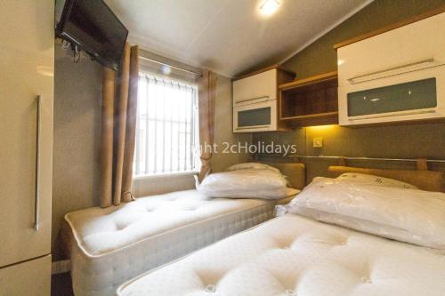 2 camas en una habitación pequeña con ventana en Luxury Lodge With Stunning Sea Views At Hopton Haven Park Ref 80055s, en Great Yarmouth