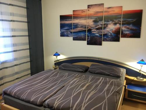 ein Schlafzimmer mit einem Bett mit vier Gemälden an der Wand in der Unterkunft Ferienwohnung Zur Sperrmauer in Edersee