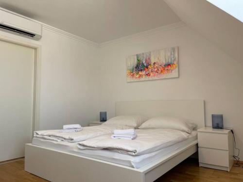 uma cama branca num quarto com uma pintura na parede em Dachgeschoss für 4 mit Terrasse em Viena