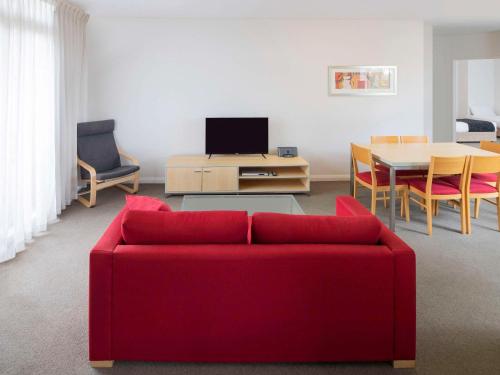 ein Wohnzimmer mit einem roten Sofa und einem Tisch in der Unterkunft Mantra Castle Hill Sydney, an Accor Hotel in Castle Hill