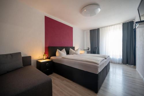 a bedroom with a bed and a couch at Hotel Ammerland garni in Wilhelmshaven