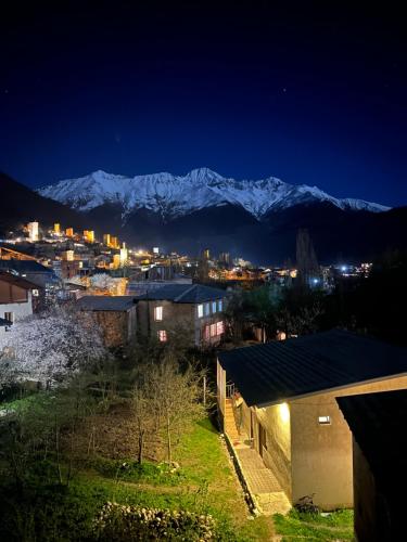 a city at night with snow capped mountains in the background at Hotel Elite House in Mestia