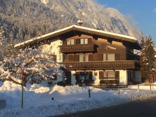 a house in the snow with a mountain in the background at Bauernhof Nagelschmiedhof in Langkampfen