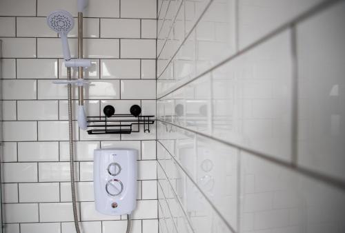 baño de azulejos blancos con ducha y cabezal de ducha en Wave Stays - Ground Floor Apartment, en Cleveleys