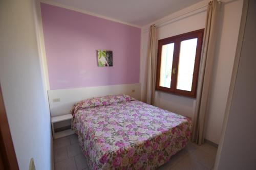 a small bedroom with a bed and a window at Bilocale SABBIA 3 - Zona mare con terrazza, clima e posta auto in Marina di Campo