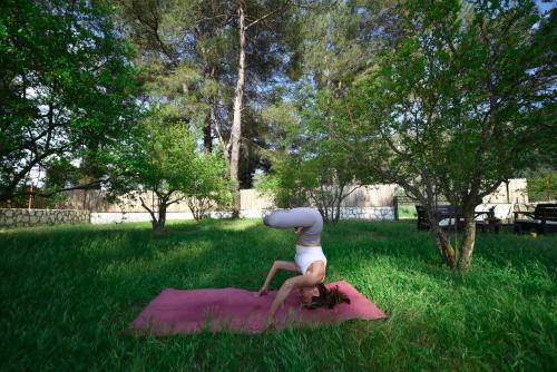 una mujer haciendo yoga en una esterilla rosa en el césped en Kas Bahce Villalari, en Kas