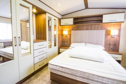 a bedroom with a large bed and a mirror at Lovely 6 Berth Caravan At Carlton Meres Holiday Park In Suffolk Ref 60021r in Saxmundham