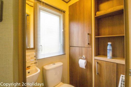 a small bathroom with a toilet and a window at Lovely 6 Berth Caravan At Carlton Meres Holiday Park In Suffolk Ref 60021r in Saxmundham