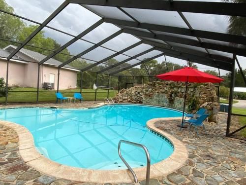 a large swimming pool with an umbrella and a red umbrella at Spacious 4 bedroom with 2 baths with Pool and boat dock in Crystal River