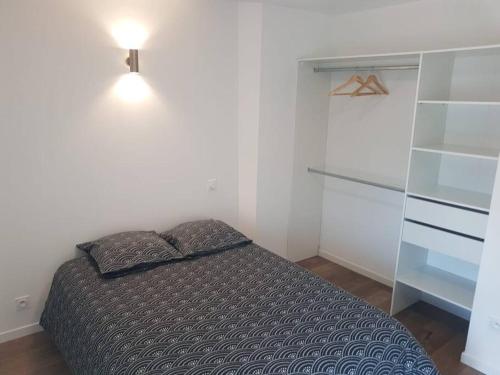 ein kleines Schlafzimmer mit einem Bett und einem Regal in der Unterkunft Appartement T2 Saint Malo, Dinard, Dinan et Dol in Miniac-Morvan