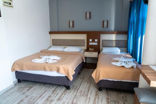 two beds in a hotel room with blue curtains at Eroglu City Hotel in Fethiye