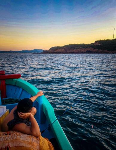 a man sitting on a boat in the water at Bãi Xếp Beach in Quy Nhon