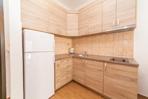 a kitchen with wooden cabinets and a white refrigerator at Welcome Apartments in Petrovac na Moru