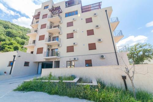 a tall white building with windows on the side of it at Welcome Apartments in Petrovac na Moru