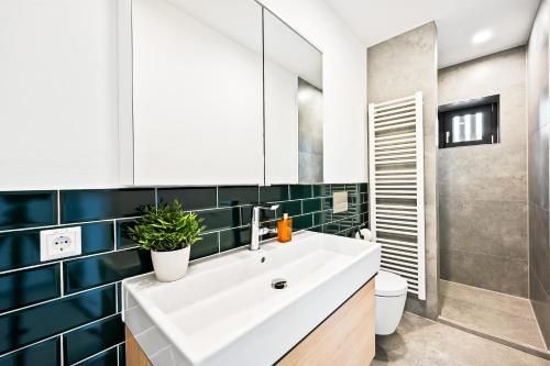 La salle de bains est pourvue d'un lavabo blanc et de carrelage bleu. dans l'établissement Lit Living - Luxus Loft - Box Spring - Air Con - BBQ - Panorama, à Mannheim